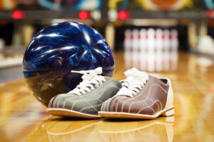 A bowling ball and shoes on the table.