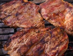 Grilled pork chops cooking on a grill.