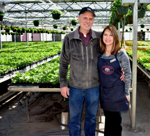 A man and woman standing in front of plants.