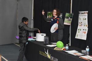 A boy and woman at an event with a white frisbee.