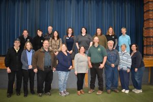 A group of people standing in front of a blue curtain.