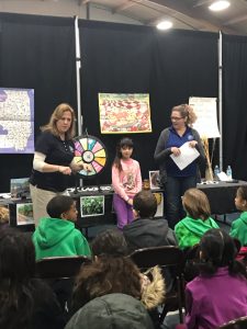 Three people standing in front of a group of children.