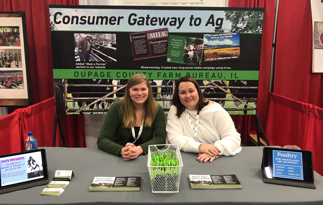 Two women sitting at a table with an advertisement for the consumer gateway to ag.