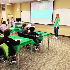 A woman teaching students in front of an interactive whiteboard.