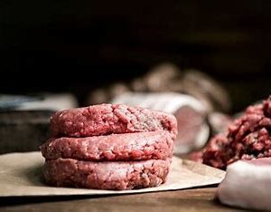 Raw beef patties on a butcher's counter.