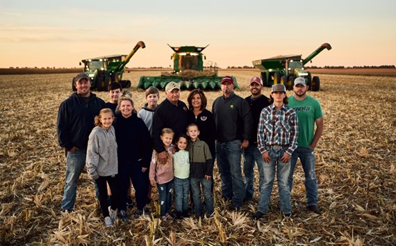 A group of people standing in front of some farm equipment.