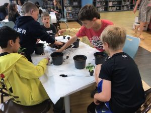 A group of children sitting around a table with plants.