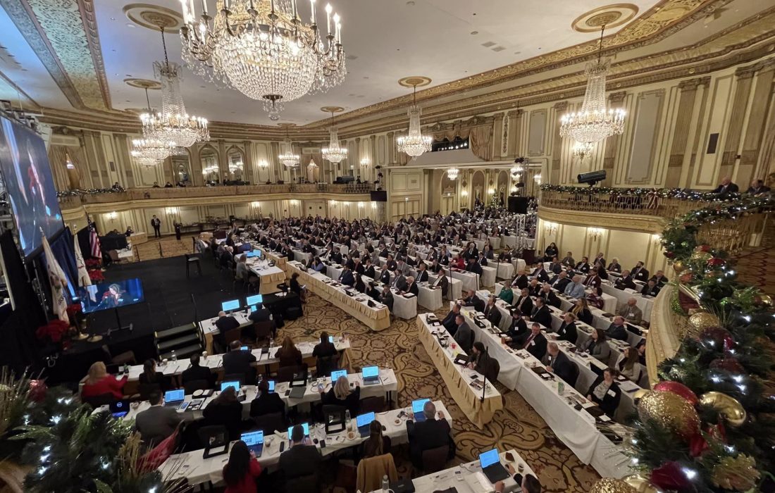 A large room with many people sitting at tables.