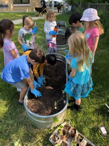 A group of children in the grass with gloves on.