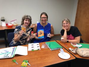 Three women sitting at a table with some books