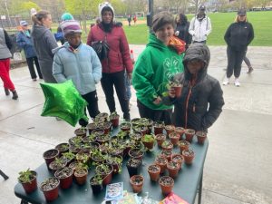 A group of people standing around a table with plants.