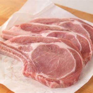 Raw pork chops on parchment paper.