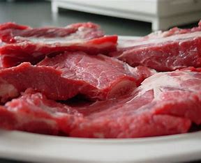 Raw beef ribs on a white plate.