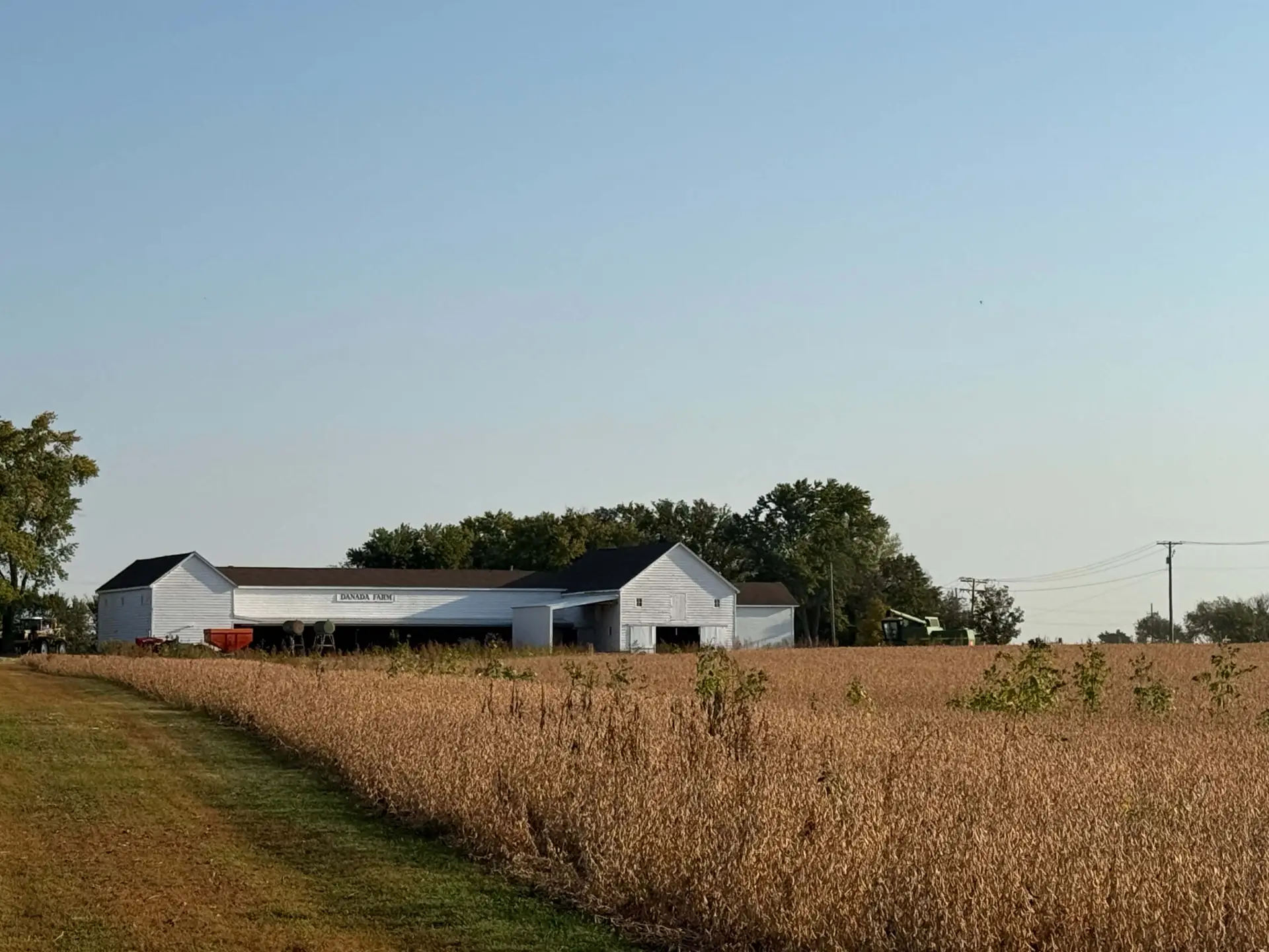 Farm buildings with field and clear sky.